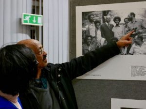 A man points at a photograph on the wall