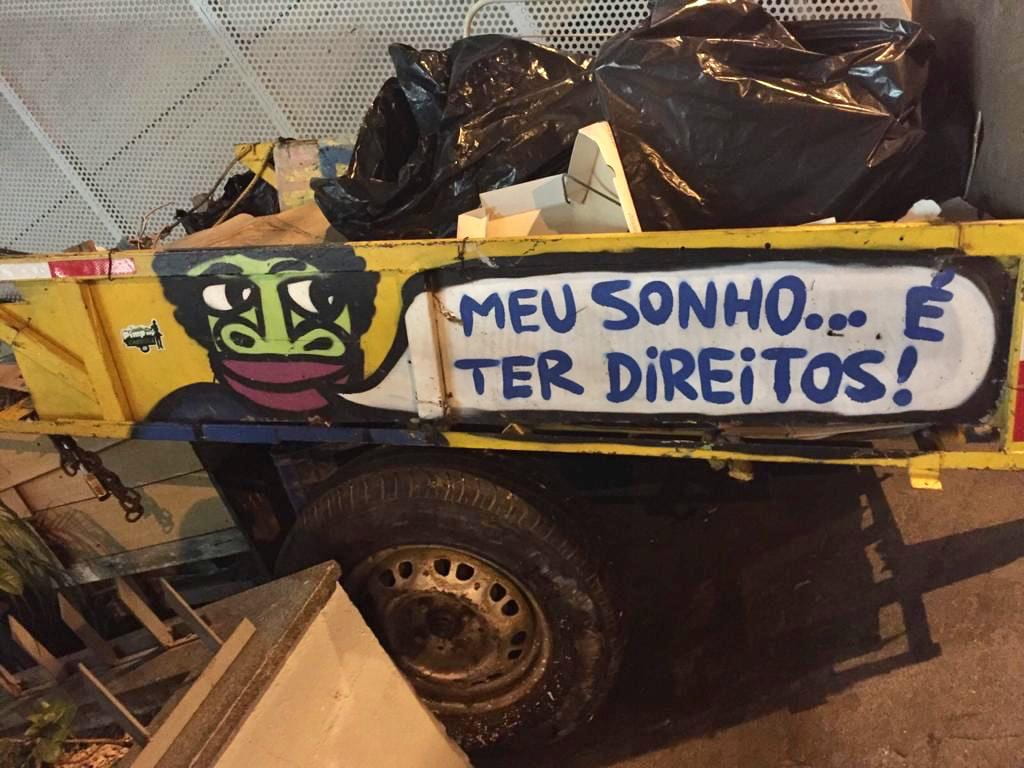 A cart on the street filled with rubbish, with painting and slogan on the side